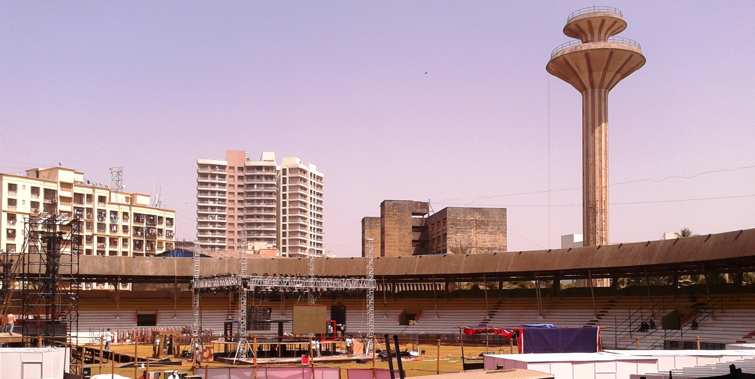 Andheri Sports Complex stadium, with tiered seating, a tall tower and surrounding apartment buildings.